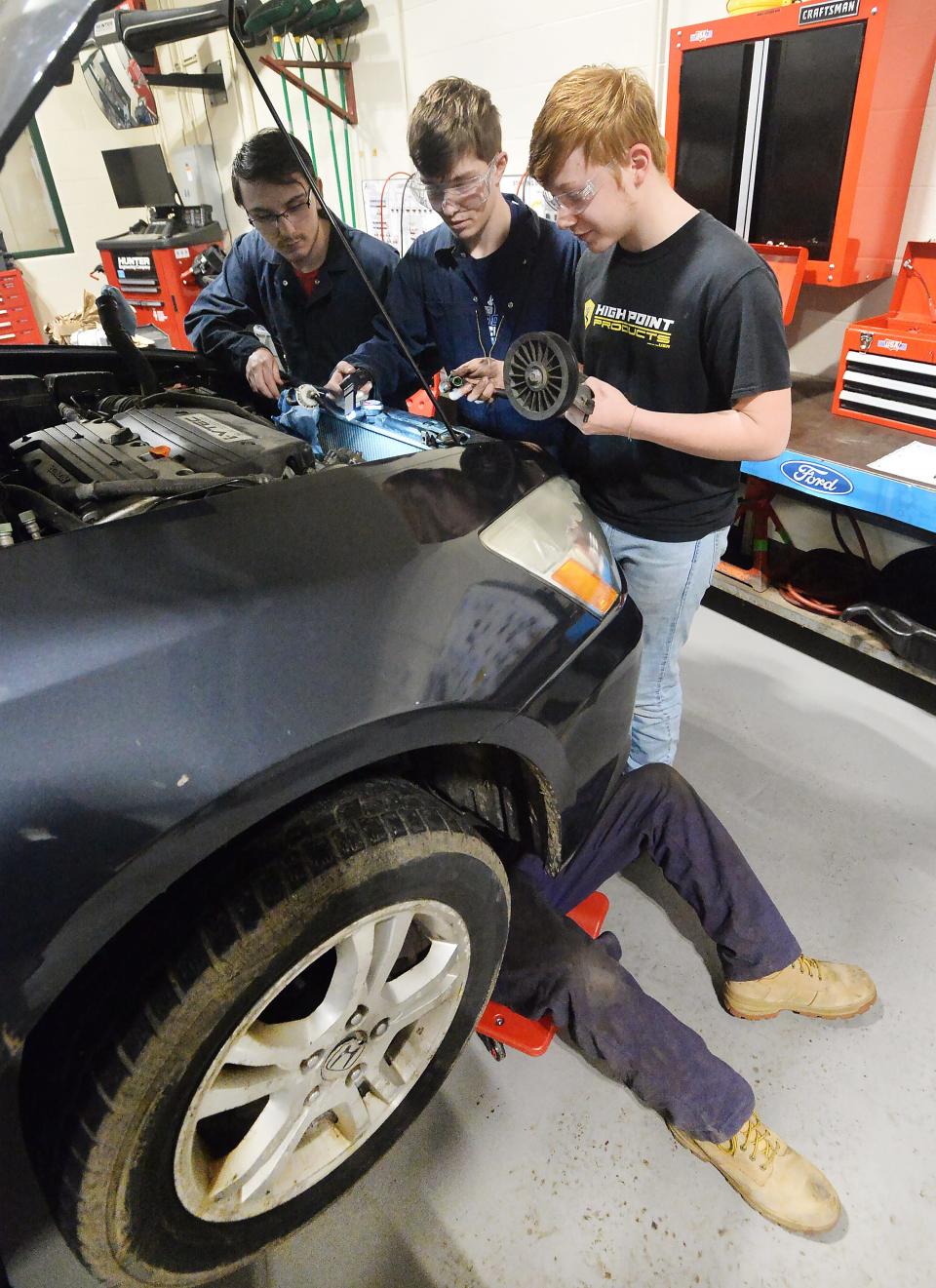 Students help install air-conditioning equipment at Erie County Technical School's new auto lab. At top, from left, are Harbor Creek senior Mike Vollmer, 18; Seneca senior Ed Butterfield, 18; and Seneca senior Aaron Jud, 18. Under the car is Terry Henderson, 17, from North East.