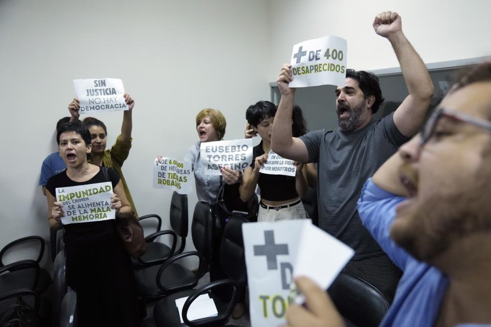 Political and human rights activists who are former detainees react as the court announces the 30-year prison sentence for retired Police Commissioner Eusebio Torres for the 1976 torture of detainees during the Stroessner dictatorship, at Justice Palace in Asuncion, Paraguay, Tuesday, Feb. 20, 2024. Torres, 88, will serve his sentence at home. The signs read in Spanish "More than 400 disappeared," "Without justice there is no democracy," and "Impunity for crime feeds a bad memory." (AP Photo/Jorge Saenz)