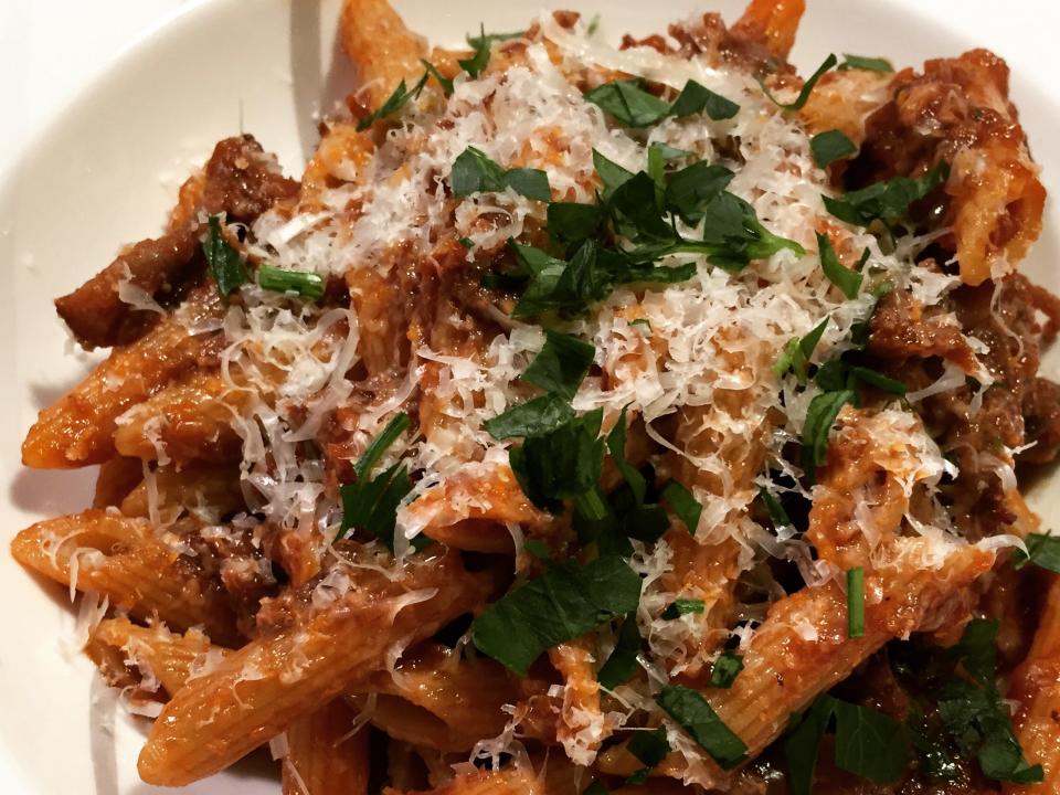 Penne pasta with a sauce and garnished with parsley and grated Parmesan