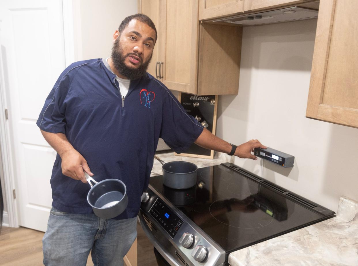 Juron Martin, program director at Midwest Health Services, shows a stove with pans that don't heat up on the outside when residents use the "smart" stove in Stark County's first "Smart Home" for people with developmental disabilities.