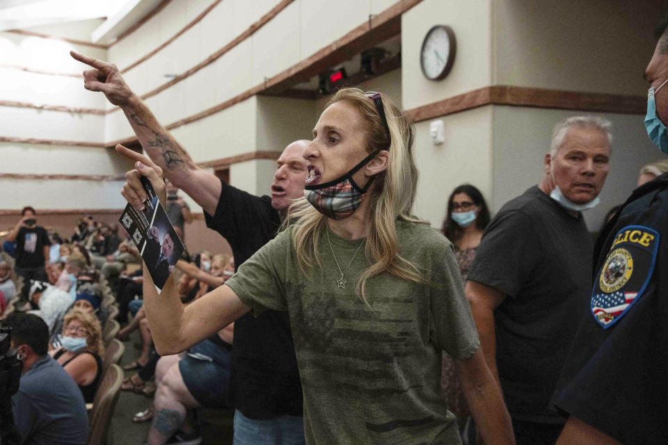 FILE - In this Aug. 12, 2021, file photo, protesters against a COVID-19 mandate gesture as they are escorted out of the Clark County School Board meeting at the Clark County Government Center, in Las Vegas. A growing number of school board members across the U.S. are resigning or questioning their willingness to serve as meetings have devolved into shouting contests over contentious issues including masks in schools. (Bizuayehu Tesfaye/Las Vegas Review-Journal via AP, File)