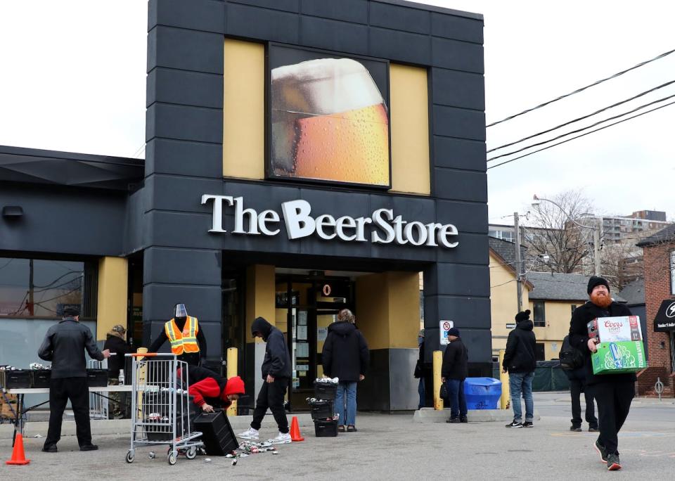 People line up in a parking lot for a long wait to return empties or buy beer at a Beer Store in downtown Toronto on April 16, 2020. 