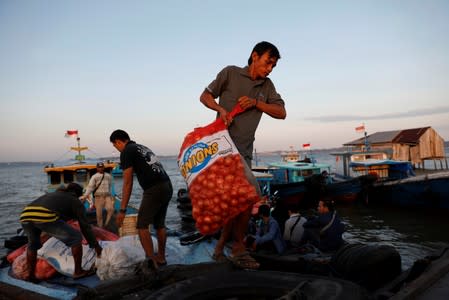People unload onions from a wooden boat as they arrive from Balikpapan at a port in North Penajam Paser regency, East Kalimantan province