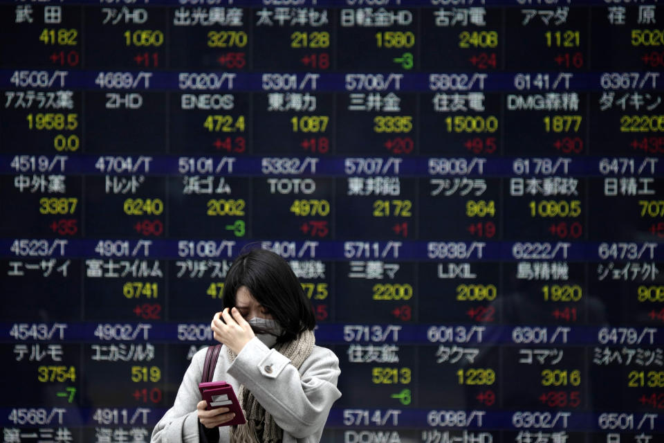 FILE - A person wearing a protective mask stands in front of an electronic stock board showing Japan's Nikkei 225 index at a securities firm in a cold morning, on Jan. 23, 2023, in Tokyo. Asian stock markets were mixed Thursday, Jan. 26, 2023 amid hopes Western economies can avoid a recession despite higher interest rates to cool inflation. (AP Photo/Eugene Hoshiko, File)