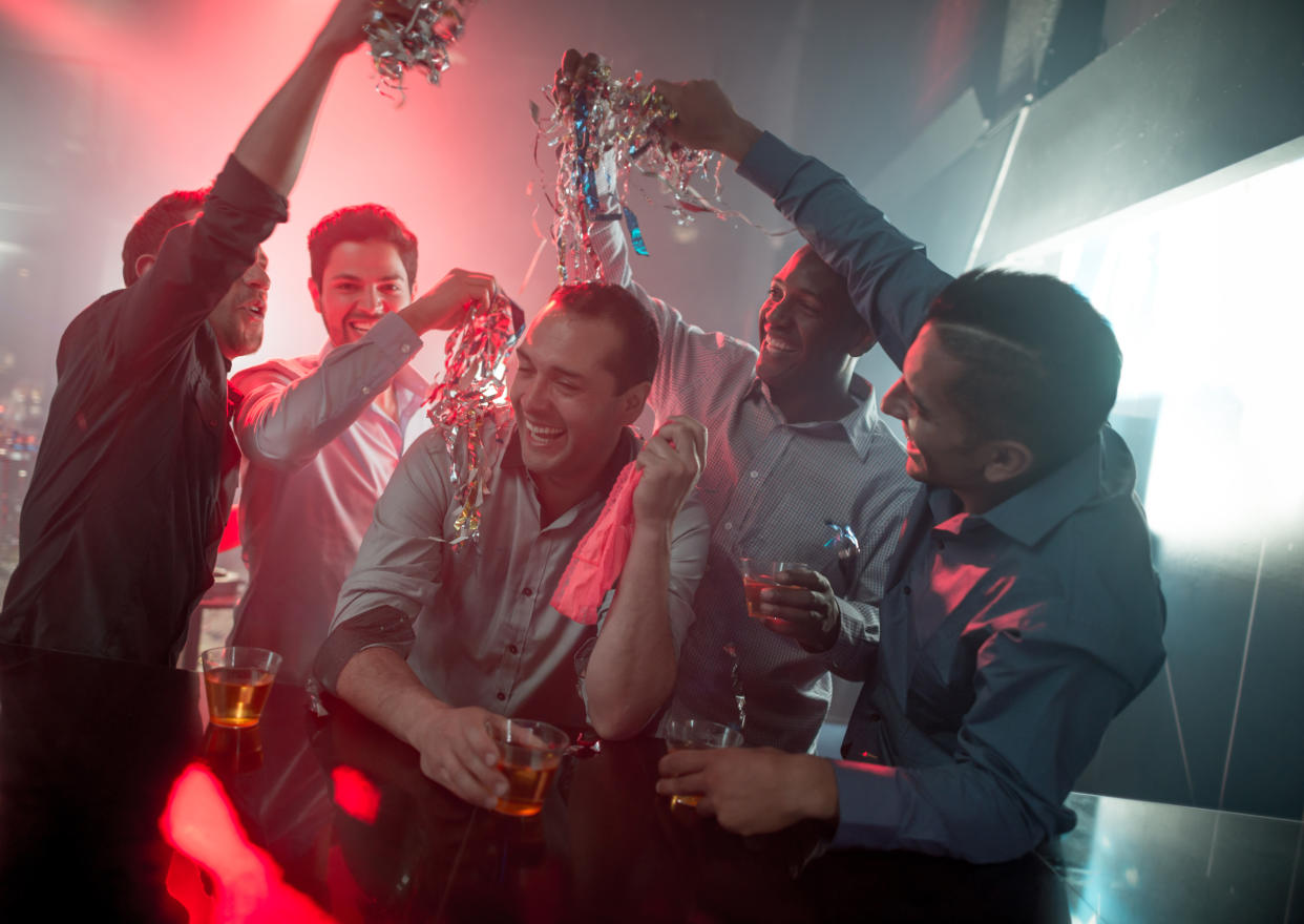 Happy group of men at a bachelor party at a nightclub having fun