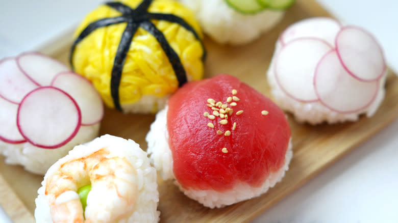 Six temarizushi sushi balls on a bamboo plate