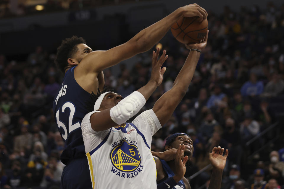 Minnesota Timberwolves center Karl-Anthony Towns (32) blocks the shot of Golden State Warriors center Kevon Looney (5) during the second half of an NBA basketball game, Sunday Jan. 16, 2022, in Minneapolis. (AP Photo/Stacy Bengs)