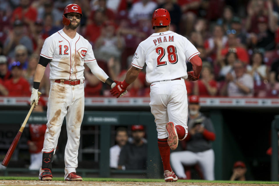 Cincinnati Reds' Tommy Pham, right, slaps hands with Tyler Naquin after scoring a run on a passed ball by Milwaukee Brewers' Omar Narvaez during the fifth inning of a baseball game in Cincinnati, Monday, May 9, 2022. (AP Photo/Aaron Doster)