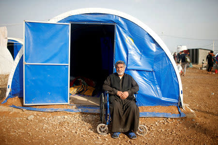 Displaced Iraqi Aziz Azawi, 50, poses for a photograph outside his tent at Hammam al-Alil camp south of Mosul, Iraq, March 29, 2017. Azawi and his son are unable to move unassisted, which made the escape even more difficult. He said a neighbour carried his son. In the camp, his wife cares for both of them. They are receiving food and medicine. They have been in the camp for about a month. REUTERS/Suhaib Salem SEARCH "DISPLACED REFUGE" FOR THIS STORY. SEARCH "WIDER IMAGE" FOR ALL STORIES.