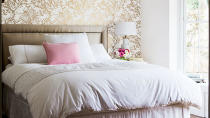 Simple bedding in this room lets the intricate wallpaper shine through.