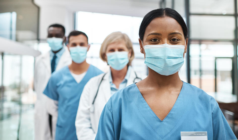 A group of medical practitioners wearing face masks while standing together in a hospital