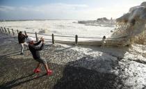 People watch huge swells as a cold front moves in over Cape Town, South Africa