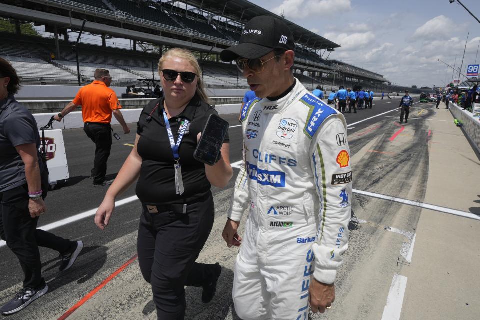 Helio Castroneves, of Brazil, is interviewed as he walks down pit lane following a practice session for the Indianapolis 500 auto race at Indianapolis Motor Speedway, Friday, May 24, 2024, in Indianapolis. (AP Photo/Darron Cummings)