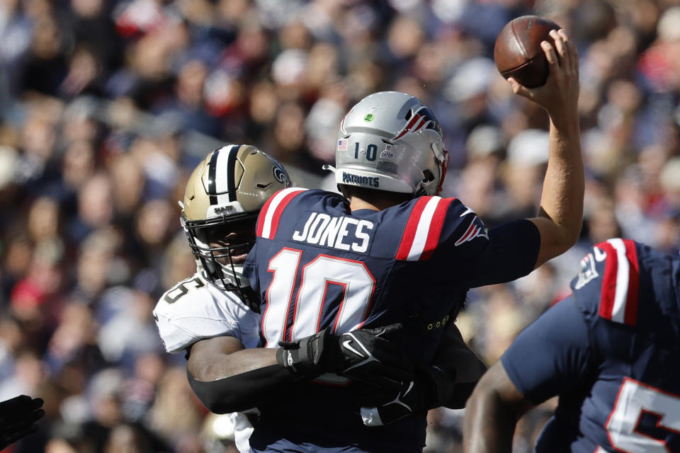 New England Patriots quarterback Mac Jones (10) tries to pass the ball under pressure from New Orleans Saints defensive end Carl Granderson, left, during the first half of an NFL football game, Sunday, Oct. 8, 2023, in Foxborough, Mass. (AP Photo/Michael Dwyer)