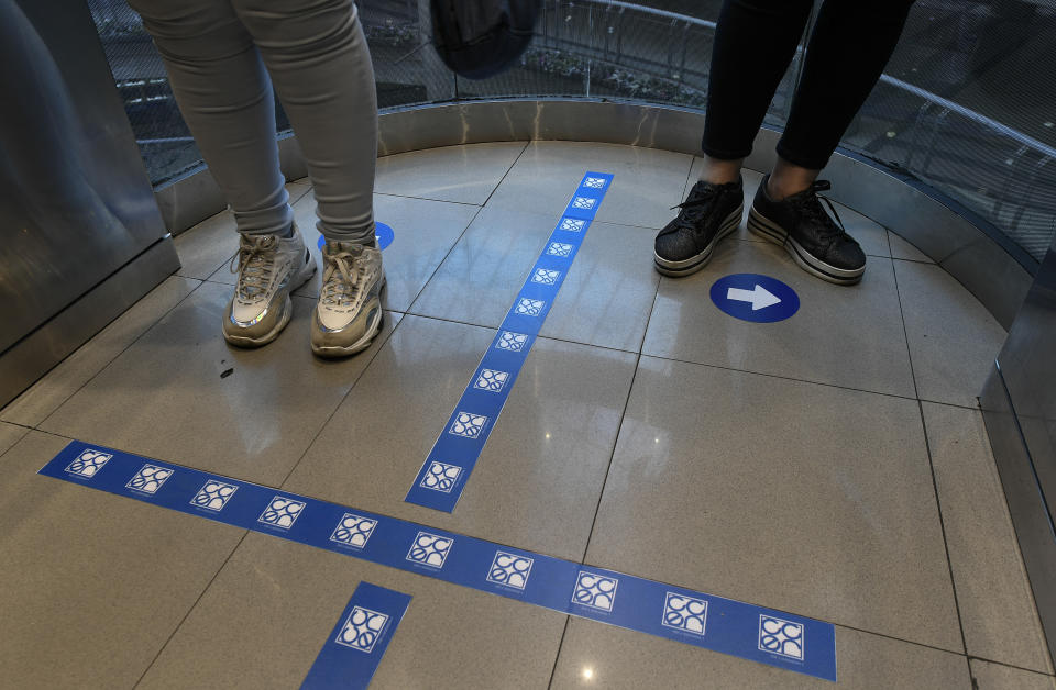 Customers stand in an elevator with the floor demarcated with social distancing stickers during a relaxation of the COVID-19 lockdown rules, at the El Recreo mall in Caracas, Venezuela, Wednesday, June 17, 2020. (AP Photo/Matias Delacroix)
