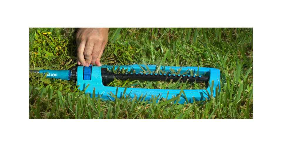 hand adjusting Aqua Joe SJI-OMS16 lawn sprinkler on lawn