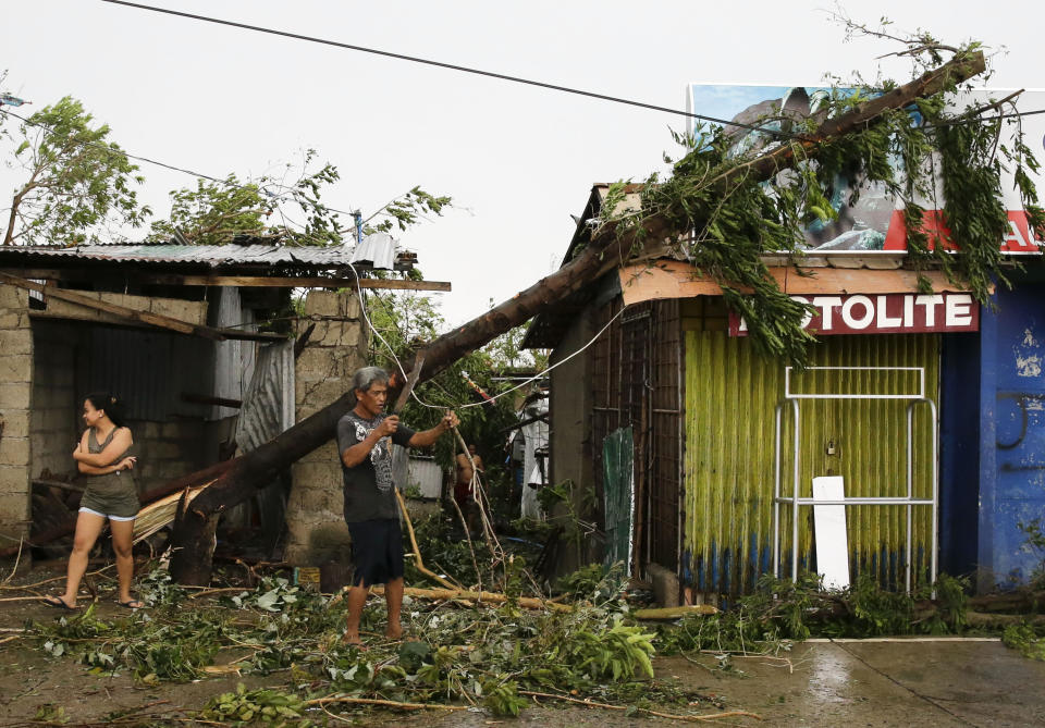FILE - In this Saturday, Sept. 15, 2018, file photo, a resident cleans up pieces from a tree that was toppled by strong winds from Typhoon Mangkhut as it barreled across Tuguegarao city in Cagayan province, the northeastern Philippines. (AP Photo/Aaron Favila, File)