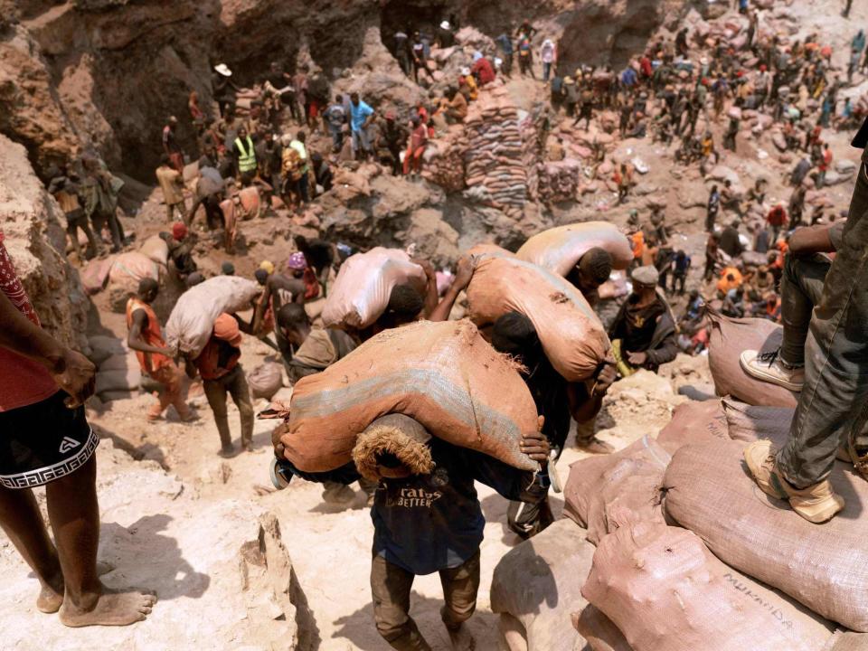 Miners carry sacks of ore at the Shabara artisanal mine