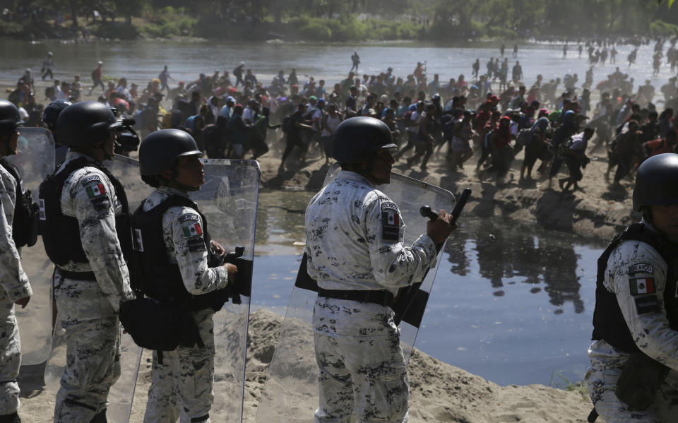 Mexican National Guards stand on the bank of the Suchiate River where Central American migrants are crossing from Guatemala, near Ciudad Hidalgo, Mexico, Monday, Jan. 20, 2020. More than a thousand Central American migrants hoping to reach the United States marooned in Guatemala are walking en masse across a river leading to Mexico in an attempt to convince authorities there to allow them passage through the country. (AP Photo/Marco Ugarte)