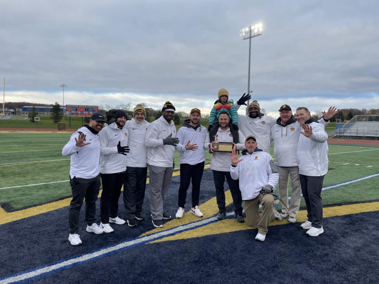 McQuaid's coaching staff, and coach Bobby Bates' son, celebrate with the Section V Class AA championship brick after a 45-15 win over UPrep. The Knights (11-0) captured their fifth straight title.