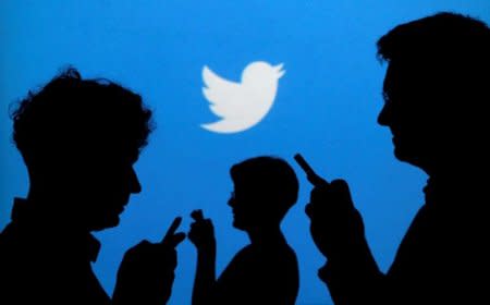 FILE PHOTO --  People holding mobile phones are silhouetted against a backdrop projected with the Twitter logo in this illustration picture taken in  Warsaw September 27, 2013.   REUTERS/Kacper Pempel/Illustration/File Photo