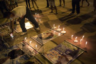 A family member places a makeshift wind protector over a candle during a vigil held for relatives who died from complications related to COVID-19 who were secretly buried in a field near the San Jose cemetery, in Iquitos, Peru, Saturday, March 20, 2021. Local authorities approved the burials but never told the families, who believed their loved ones were buried in the local cemetery — and only months later discovered the truth. (AP Photo/Rodrigo Abd)