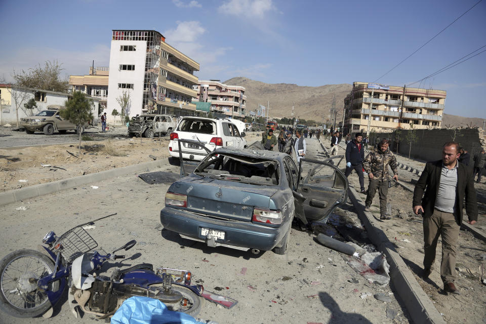 FILE- in this Wednesday, Nov. 13, 2019, file photo, Afghan security personnel gather at the site of a car bomb attack in Kabul, Afghanistan. Afghanistan will need vast amounts of foreign funding to keep its government afloat through 2024, a U.S. agency said Thursday, even as foreign donors are increasingly angry over the cost of debilitating corruption and the U.S. seeks a peace deal with Taliban to withdraw its troops. (AP Photo/Rahmat Gul, File)