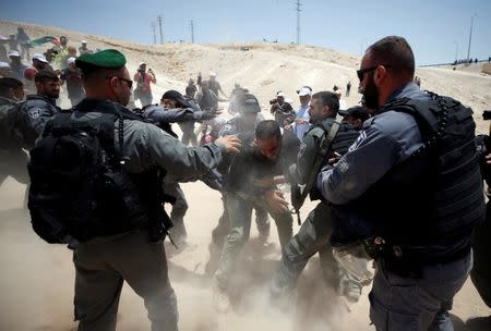 Israeli policemen scuffle with a Palestinian in the Bedouin village of al-Khan al-Ahmar near Jericho in the occupied West Bank July 4, 2018. REUTERS/Mohamad Torokman