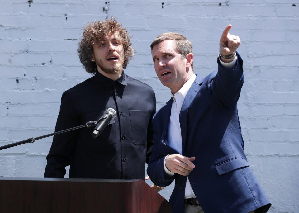 Gov. Andy Beshear, right, joked about having a banner of himself near rap music star and Louisvillian Jack Harlow's Hometown Heroes banner during the official unveiling at the corner of Broadway and Barrett Ave. in Louisville, Ky. on May 3, 2023.