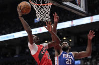 El alero de los Raptors de Toronto Chris Boucher lanza el balón mientras lo defiende Joel Embiid de los 76ers de Filadelfia en el encuentro del jueves 7 de abril del 2022. (Frank Gunn/The Canadian Press via AP)