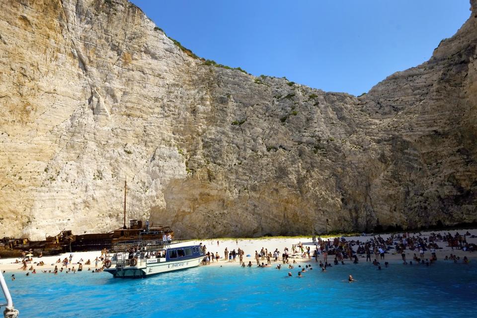 FILE - In this Friday, Sept. 8, 2017 file photo, people enjoy the popular beach of Navagio, or Shipwreck Beach, on the western island of Zakynthos, Greece. Scientists say that half of the world's sandy beached are at risk of disappearing by the end of the century if climate changes continues unchecked. Researchers at the European Union's Joint Research Center in Ispra, Italy, used satellite images to track the way beaches changed over the past 30 years and project how global warming might affect them in the future. (AP Photo/Petros Karadjias, File)