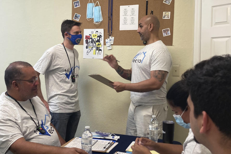 Alex Berrios, right, co-founder of the nonprofit Mi Vecino, coaches newly hired staff member Colby Snaidman, right, on how best to approach people and convince them to register to vote on Thursday, June 24, 2021, in Kissimmee, Fla. Mi Vecino, and other advocacy organizations affiliated with Democrats, are trying to engage Latino voters earlier and build lasting relationships after Republicans gained ground with voters in some Latino communities during last year's presidential and congressional races. (AP Photo/Will Weissert)