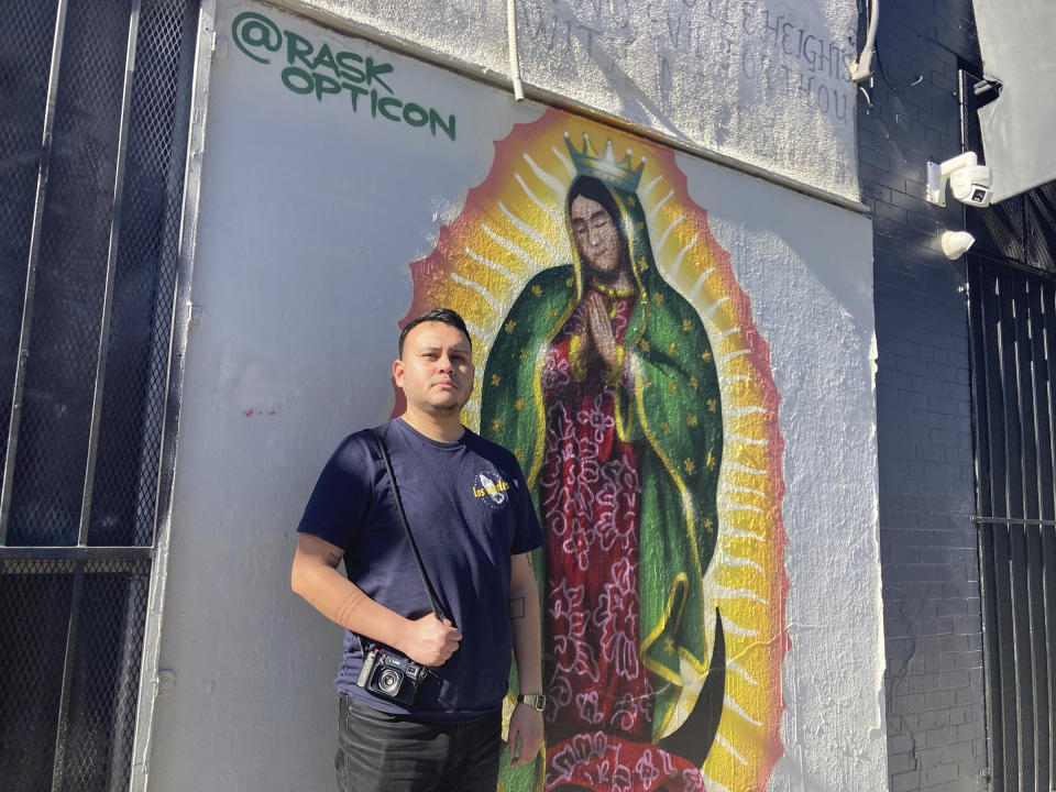 Oscar Rodriguez Zapata posa al lado de una imagen de la Virgen de Guadalupe pintada en una pared en Los Ángeles, el sábado 21 de enero de 2023. (Alejandra Molina/Religion News Service vía AP)