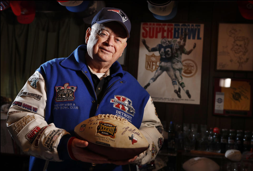 FILE — Donald Crisman poses with memorabilia from Super Bowls he has attended so far, Thursday, Jan. 25, 2018, at his home, in Kennebunk, Maine. Crisman, along with Tom Henschel, and Gregory Eaton have attended every Super Bowl since the first AFL-NFL World Championship held 55 years ago. The three men are meeting at the Super Bowl once again for this year's game, but future meetings are in question. (AP Photo/Robert F. Bukaty, File)