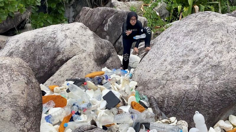 A woman clears trash by the sea at Tioman Island, Pahang, Malaysia