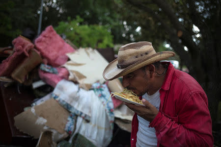 Ruben Morales eats dinner without using utensils after clearing furniture from the house of a neighbor left flooded by Tropical Storm Harvey in Houston, Texas, U.S. September 4, 2017. REUTERS/Adrees Latif