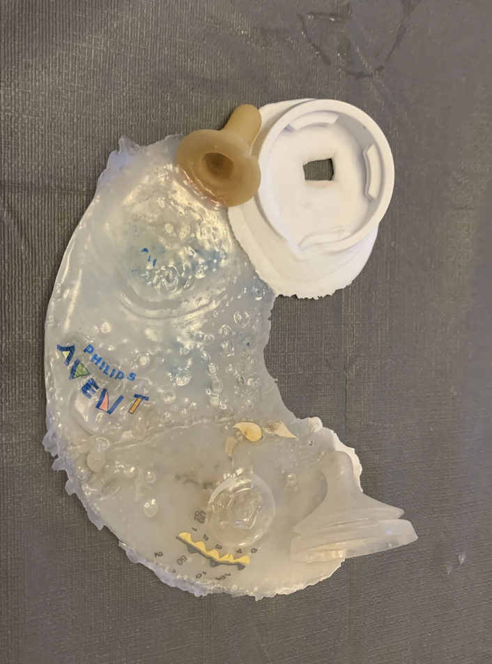 A melted plastic baby bottle with the nipple on top