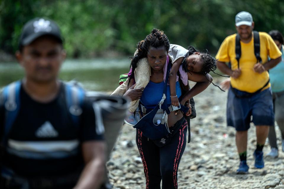 A migrant woman walks by the jungle carrying her daughter near Bajo Chiquito village, the first border control of the Darien Province in Panama, on September 22, 2023. / Credit: LUIS ACOSTA/AFP via Getty Images