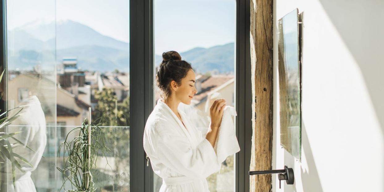 smiling woman cleaning her hands with white towel personal hygiene and morning routine