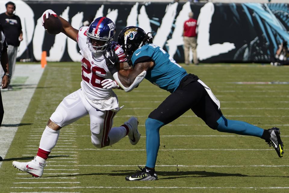 New York Giants running back Saquon Barkley (26) gets shoved out of bounds by Jacksonville Jaguars safety Rayshawn Jenkins (2) during the second half of an NFL football game Sunday, Oct. 23, 2022, in Jacksonville, Fla. (AP Photo/John Raoux)