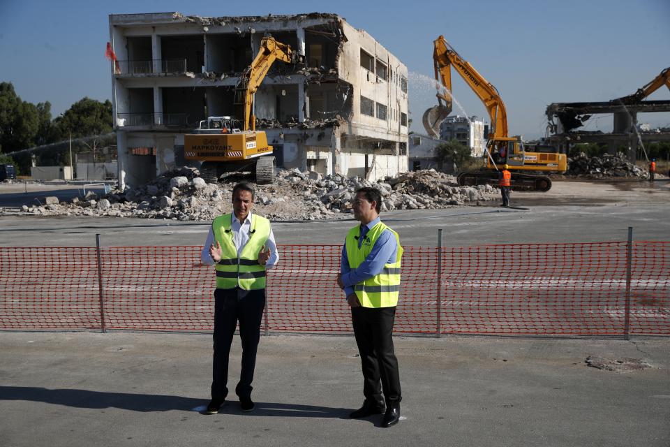 Greece's Prime Minister Kyriakos Mitsotakis, left, speak as CEO of Lamda Development Odisseas Athanasiou listens him during the demolition of the first abandoned buildings at the old airport in Athens, Friday, July 3, 2020. Mitsotakis inaugurated the start of construction work on a long-delayed major development project at the prime seaside site of the old Athens airport. The development of the 620-hectare (1,500-acre) Hellenikon site was a key element of the privatization drive that was part of Greece's international bailouts. (AP Photo/Thanassis Stavrakis)