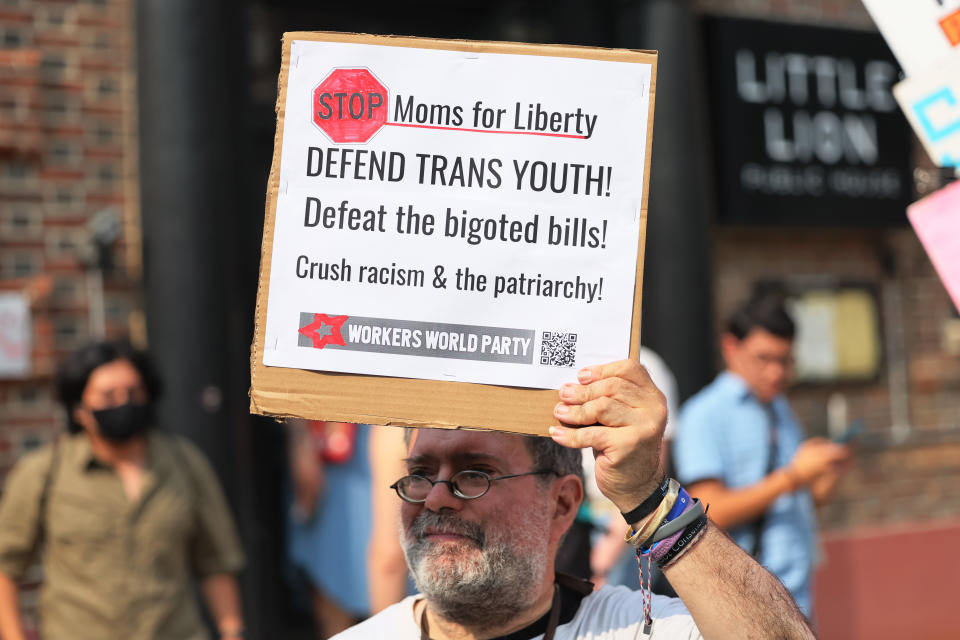 At a protest outside the Moms for Liberty conference in Philadelphia, a man holds a sign saying: Stop Moms for Liberty, Defend Trans Youth. 