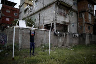 Nicolas Suárez, de 16 años, posa para un foto al colgarse de un arco en una cancha de fútbol cerrada por por la pandemia de COVID-19 en la villa de Fraga de Buenos Aires, Argentina, el sábado 6 de junio de 2020. (AP Foto/Natacha Pisarenko)