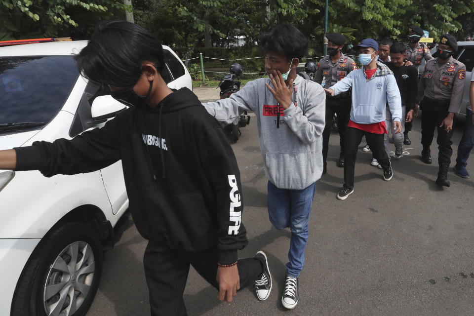 Protesters are led by police after being detained during a rally against the new jobs law in Jakarta, Indonesia, Tuesday, Oct. 20, 2020. Protests against Indonesia's new jobs law were held in cities across the country on Tuesday, with demonstrators calling on the president to revoke the legislation they say will erode labor rights and weaken environmental protections. (AP Photo/Achmad Ibrahim)