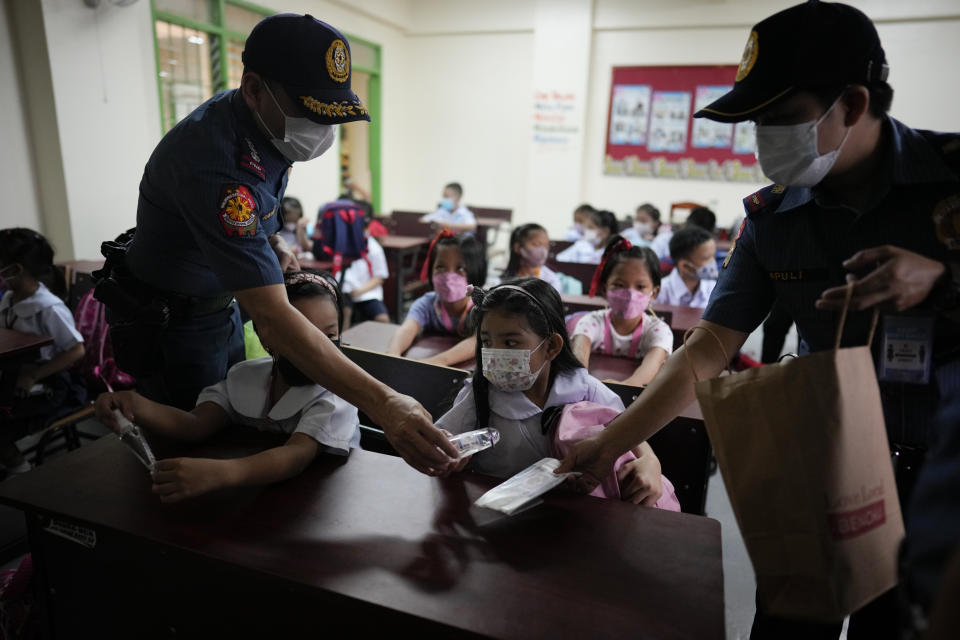 Police distribute alcohol and face masks to students during the opening of classes at the San Juan Elementary School in metro Manila, Philippines on Monday, Aug. 22, 2022. Millions of students wearing face masks streamed back to grade and high schools across the Philippines Monday in their first in-person classes after two years of coronavirus lockdowns that are feared to have worsened one of the world's most alarming illiteracy rates among children. (AP Photo/Aaron Favila)