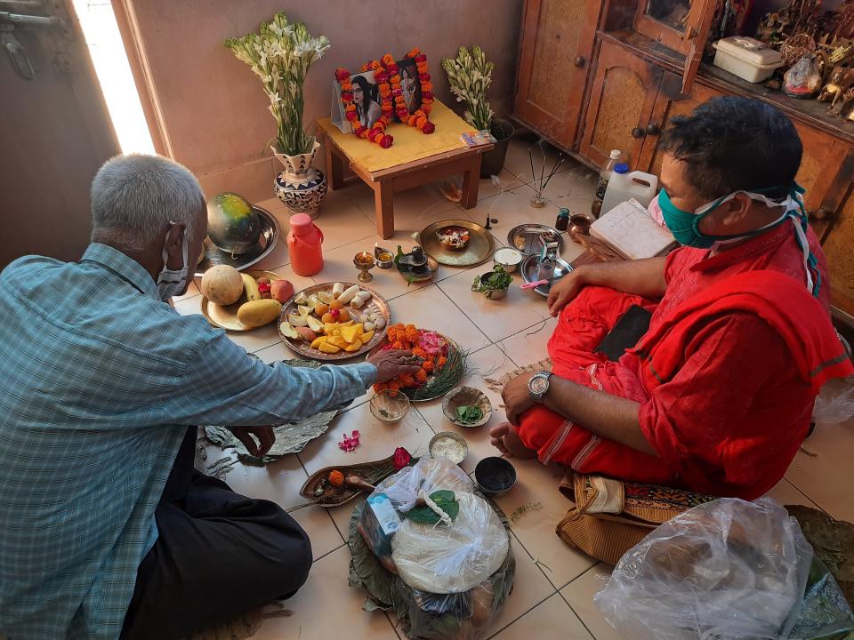 Radha Gobindo Pramanik, left, performs a Hindu ritual for his wife and daughter who died of COVID-19 at his home in Lucknow, India, May 23, 2021. “Everyone whom I loved the most has left me,” the 71-year-old said on a recent night as a Hindu priest chanted mantras and performed a ritual for the dead at his home in the northern city of Lucknow. “I am left alone in this world now.” (AP Photo/Rajesh Kumar Singh)