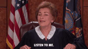 Judge Judy sitting her her court chair mouthing the words listen to me I'm gonna tell you something