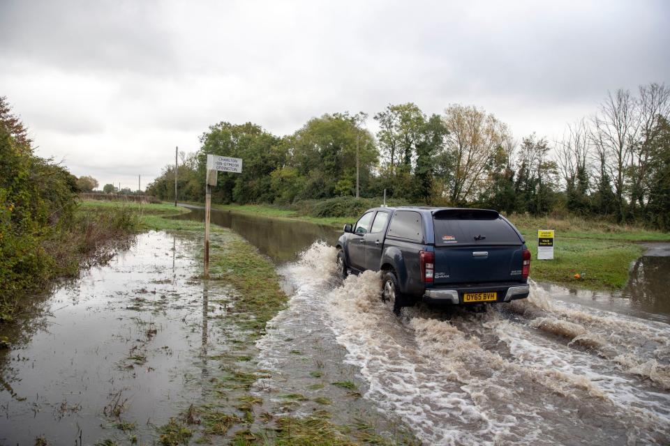 A car drives through a flooded road near Oddington in Oxfordshire. (PA)