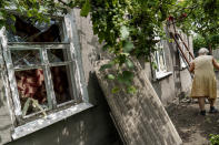 Nadiia Vasylivna, 70, walks by the blown out windows of her home from a rocket strike next door in Kramatorsk, Donetsk region, eastern Ukraine, Friday, Aug. 12, 2022. (AP Photo/David Goldman)