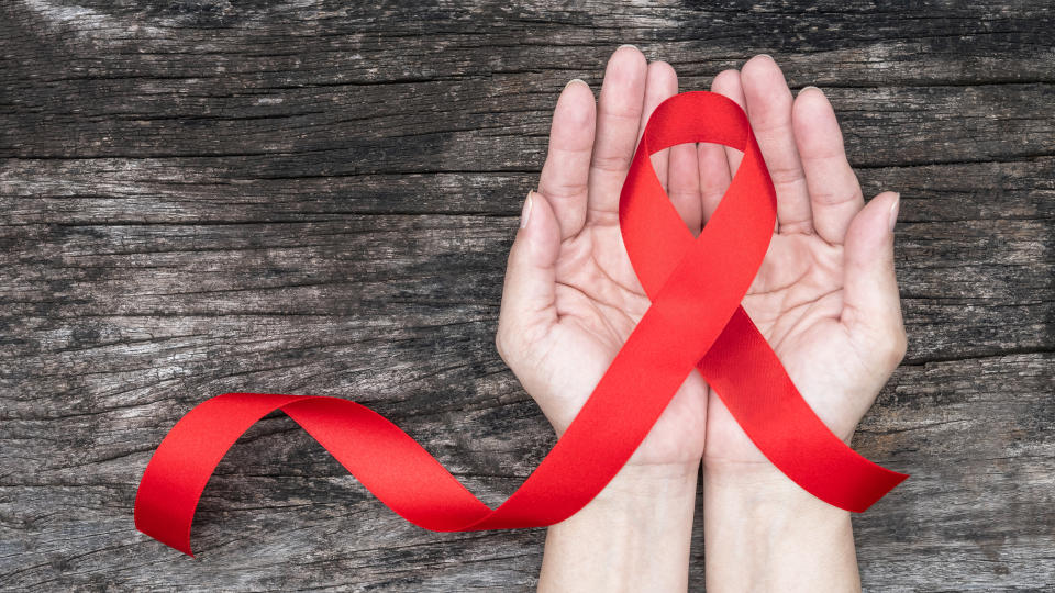 World aids day and national HIV/AIDS and ageing awareness month with red ribbon on woman hand support (bow isolated with clipping path)